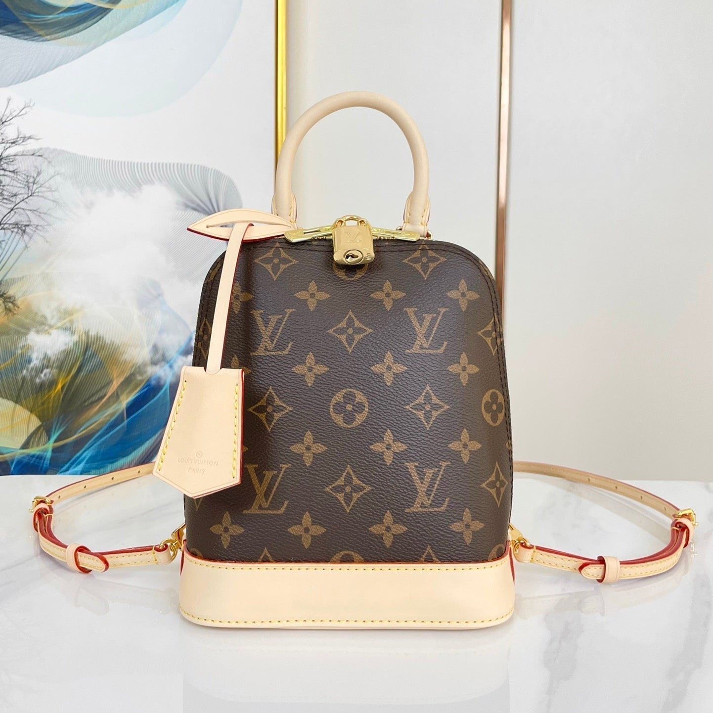 ALMA RUCKSACK 20 IN BRAUNEM MONOGRAMM-CANVAS UND BEIGEM KALBSLEDERBESATZ MIT GOLDENER SCHNALLE